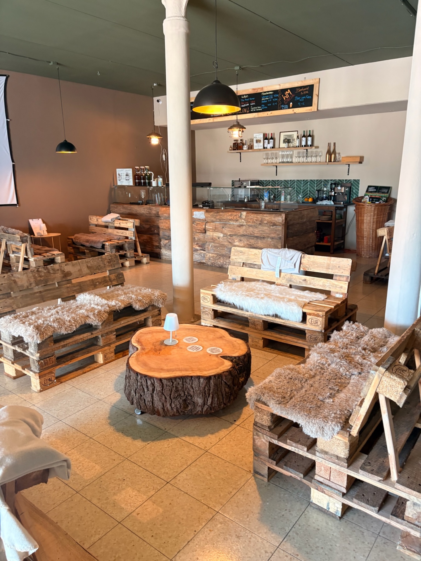 Innenraum der Lager-Bar mit Palettenlounge und Baumscheiben-Tisch